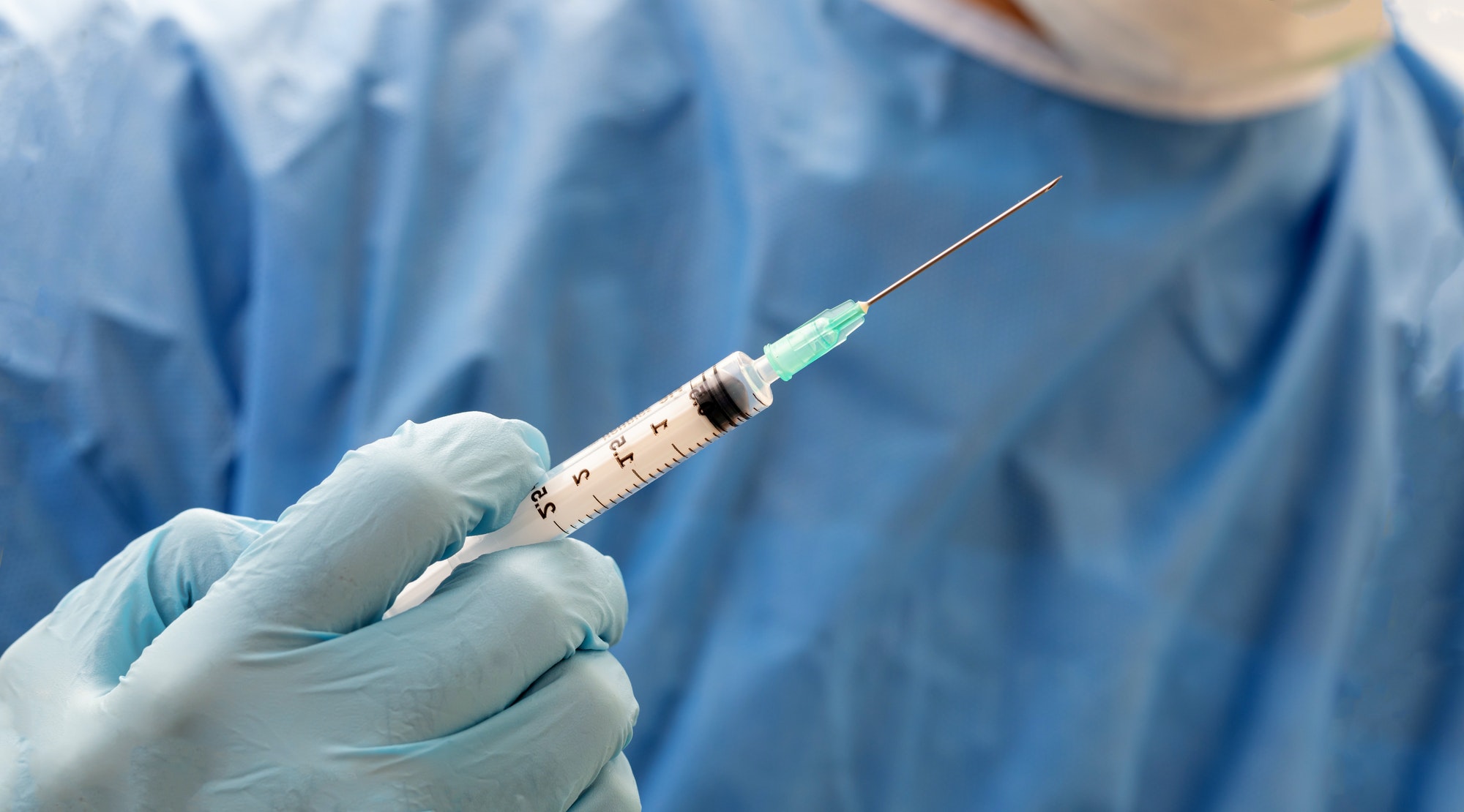 Doctor hand injecting treatment dose with syringe closeup